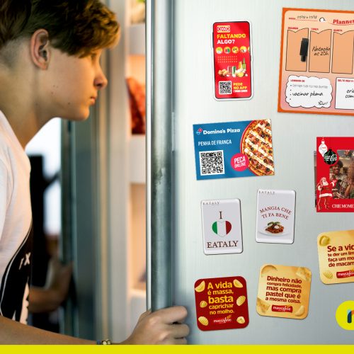 Jovem abrindo geladeira com ímãs criativos